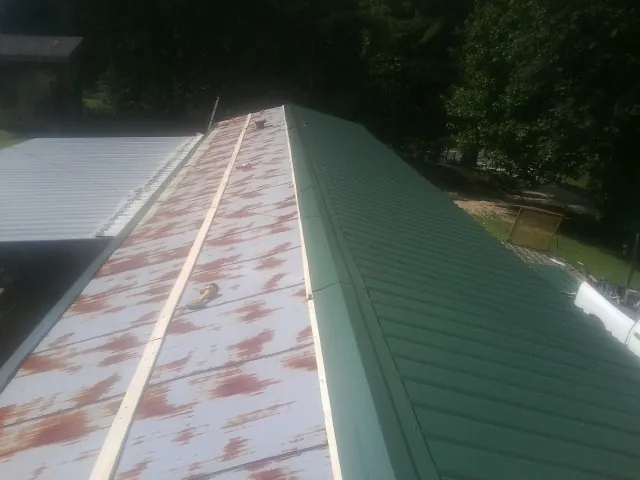 Old rusted panels beside newly installed green metal roofing — Wind Damage Roof Repair by Roofing Brothers in Estill