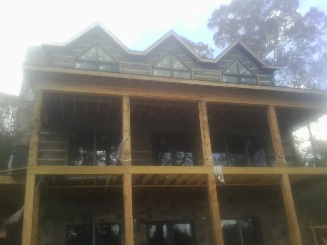 Dormers and porch framing on a large log home under construction — Roof Coating work by our crew in Estill