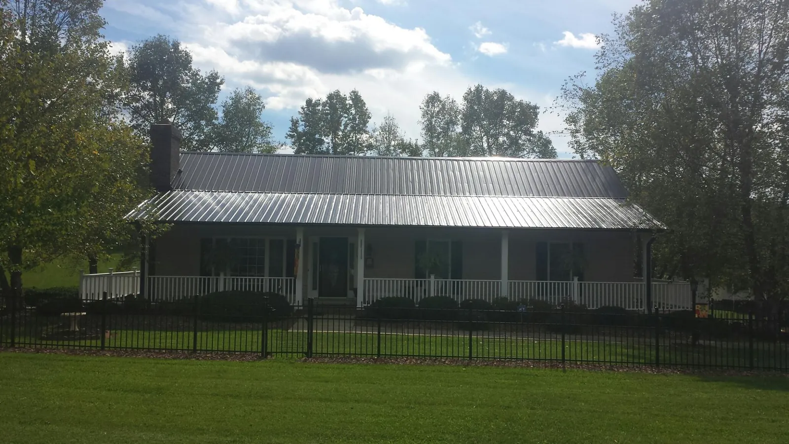 Gray metal roof on a brick ranch with a full width front porch — Gutter Guard Installation work by our crew in Estill