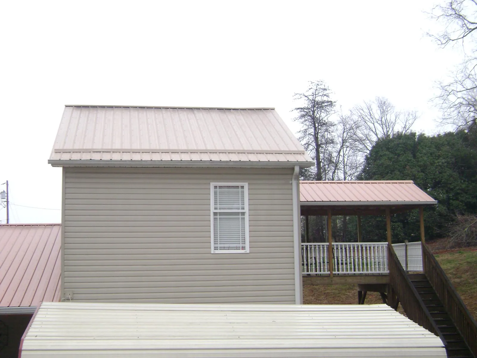 Tan metal roofs on a two story addition and attached porch, from a Roof Replacement job in Estill